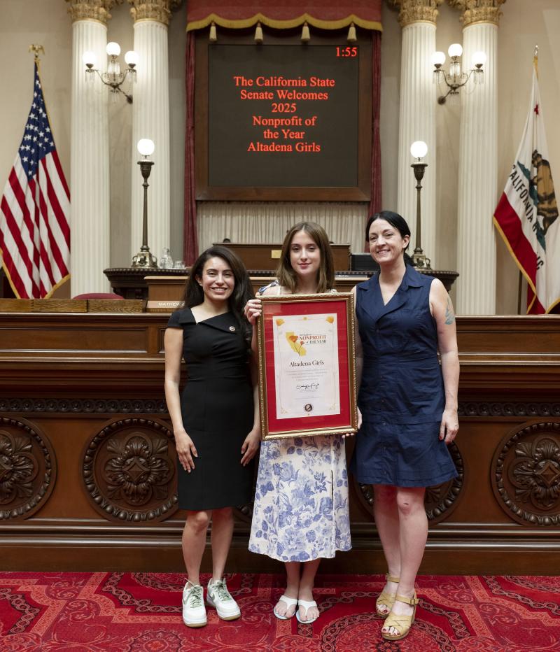 Senator Perez standing with honorees holding framed resolution on Senate Floor